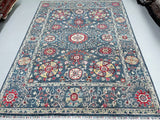 A decorative, full-room size handcrafted Afghan Ziegler Chobi rug with a floral design in green/blue, beige, yellow, and maroon tones, featuring a traditional Serapi pattern.