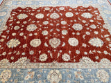 A hand-knotted Afghan Chobi rug featuring a floral pattern with terracotta, beige, and grey blue tones on a red and blue background.