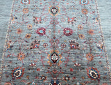 A detailed image of a Sultani Afghan Chobi rug featuring a geometric and floral pattern in various colors including blue, red, and gold, woven in Afghanistan.