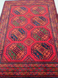 A vibrant red and blue tribal Afghan Ersari rug with geometric elephant foot medallions design, featuring a burnt terracotta background.