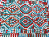A hand woven Afghan Kyber Kilim rug with a geometric diamond medallion design in beige, red, aqua, and green tones.