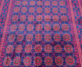 A tribal-patterned Afghan rug featuring a geometric medallion design in red, blue, and green on a dark blue background at Persian rug warehouse WA in Perth.
