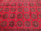 A close-up of a traditional red and brown tribal Afghan Kunduz rug with a geometric medallion design.