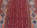 A close-up of a traditional Khorjin Afghan Super Kazak rug with a geometric pattern, predominantly in red and blue tones, showcasing its intricate design.