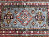 A multicolored, handmade Afghan Royal Kazak rug with geometric patterns and a rich pile.