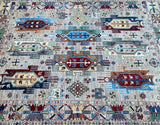 A detailed shot of a traditional Afghan Super Kazak rug with geometric patterns and a variety of colors including beige, blue, and red.