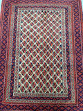 A certified handmade Persian prayer rug with a geometric pattern in red, blue, and orange hues, and a border in a contrasting color.