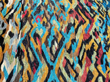 A close-up of a contemporary handmade Afghan Gabbeh rug with a geometric pattern featuring multiple colors including beige, yellow, green, black, red, blue, and brown.