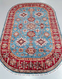 An oval-shaped, hand-knotted wool rug with a geometric pattern in blue and red tones, featuring a traditional Kazak design.