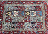 A hand-knotted Persian Birjand rug with a multicolor tone and floral and geometric patterns on a red background.