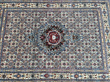 A hand-knotted Persian rug with a floral and geometric pattern in beige, blue, orange, black, red, and pink tones.