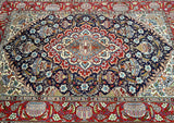 A handmade Persian Kashmar rug with a geometric pattern in red, blue, and green colors on an indigo blue background.