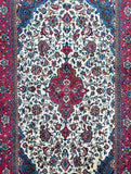 Close-up of a Persian Sarough rug with a detailed floral pattern in beige, blue, red, brown, orange, and pink tones.