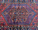 A traditional Persian Zanjan rug with a geometric medallion design in the center, featuring a combination of red, navy blue, beige, green, and brown colors.