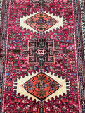 A vibrant, multicolored Persian hall runner rug featuring geometric patterns and animal motifs.