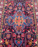 A vibrant, multicolored tribal Persian rug with a geometric pattern and animal motifs, predominantly in blue and red tones.