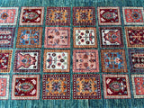 A variety of square-shaped Afghan Super Kazak rugs with a floral and geometric pattern, predominantly in red, green, and blue colors, displayed together.
