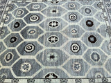 A handmade Afghan Turkoman rug with a geometric pattern in shades of gray, charcoal, beige, and black, featuring intricate geometric designs.